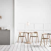 Minimalist white walls, light wood furniture, and soft neutral tones create a serene dining atmosphere.