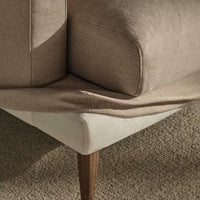 Beige and cream couch corner with soft texture and angled wooden legs, blending modern and classic design elements.