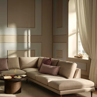 Beige sectional sofa with plum accent pillows, set against a soft beige and taupe wall with elegant molding.