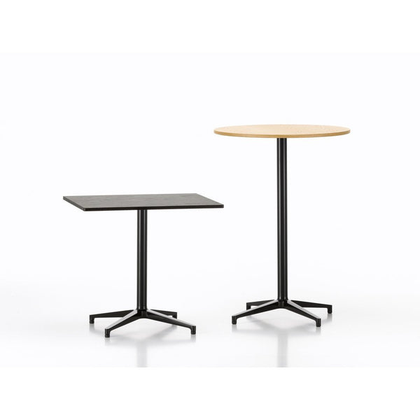 Two modern tables featuring a round natural wood top and a square black top with sleek black metal bases.
