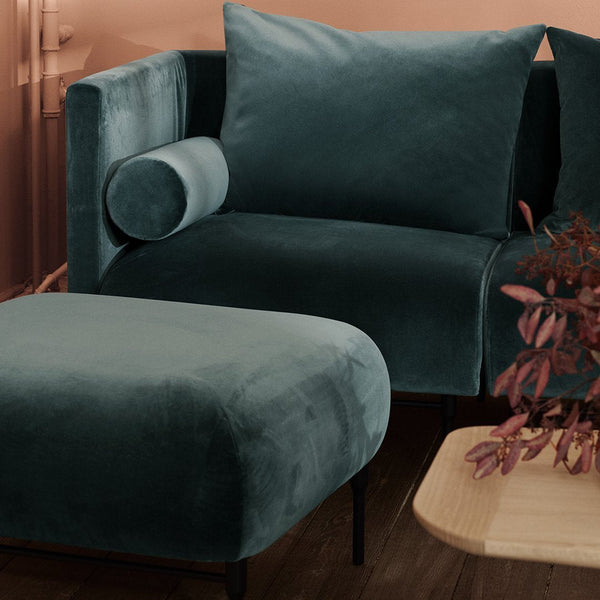 Teal velvet sofa and ottoman with soft textures, perfect for modern decor.