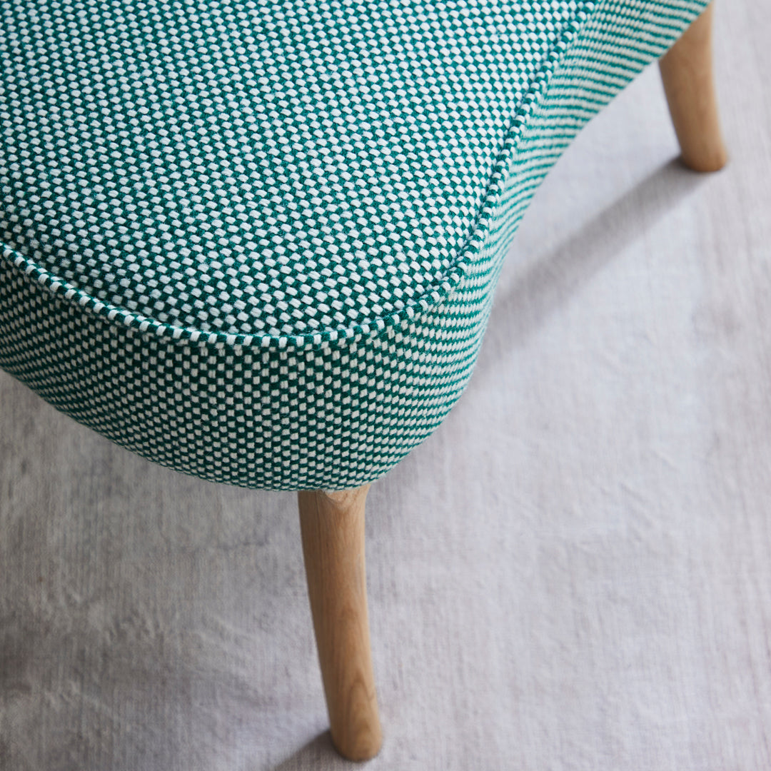 Green and white houndstooth patterned upholstery with light wooden legs. Stylish and modern accent chair design.