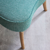 Green and white houndstooth patterned upholstery with light wooden legs. Stylish and modern accent chair design.