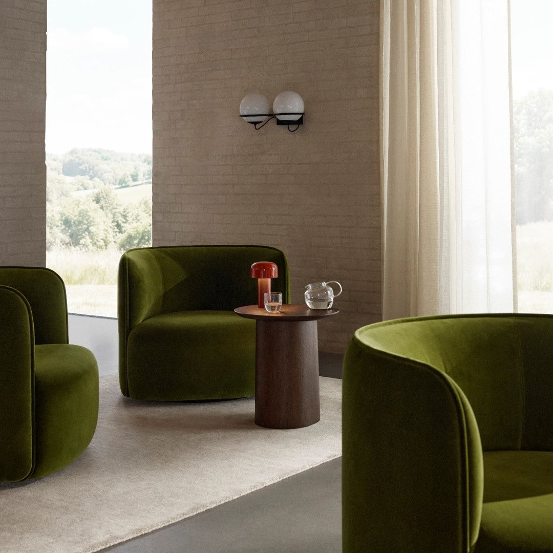 Luxurious olive green velvet armchairs with modern, curved shapes in a contemporary, airy setting.