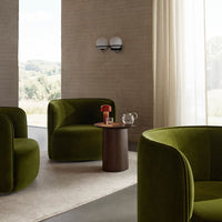 Luxurious olive green velvet armchairs with modern, curved shapes in a contemporary, airy setting.