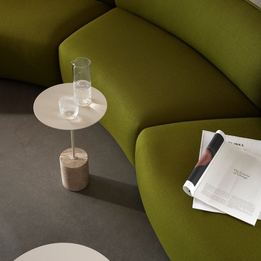 Curved olive green couch with subtle textures, paired with a minimalist white side table and stone base.