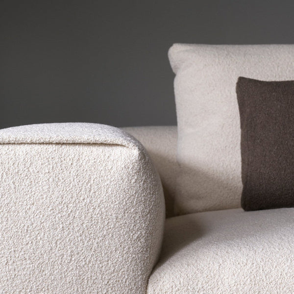 Textured cream sofa arm with a contrasting dark brown cushion against a neutral background. Perfect for modern decor.