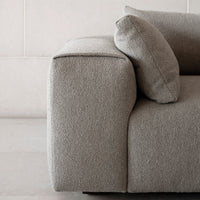 Soft gray textured fabric sofa with clean lines and a minimalist design accentuated by a round cushion.