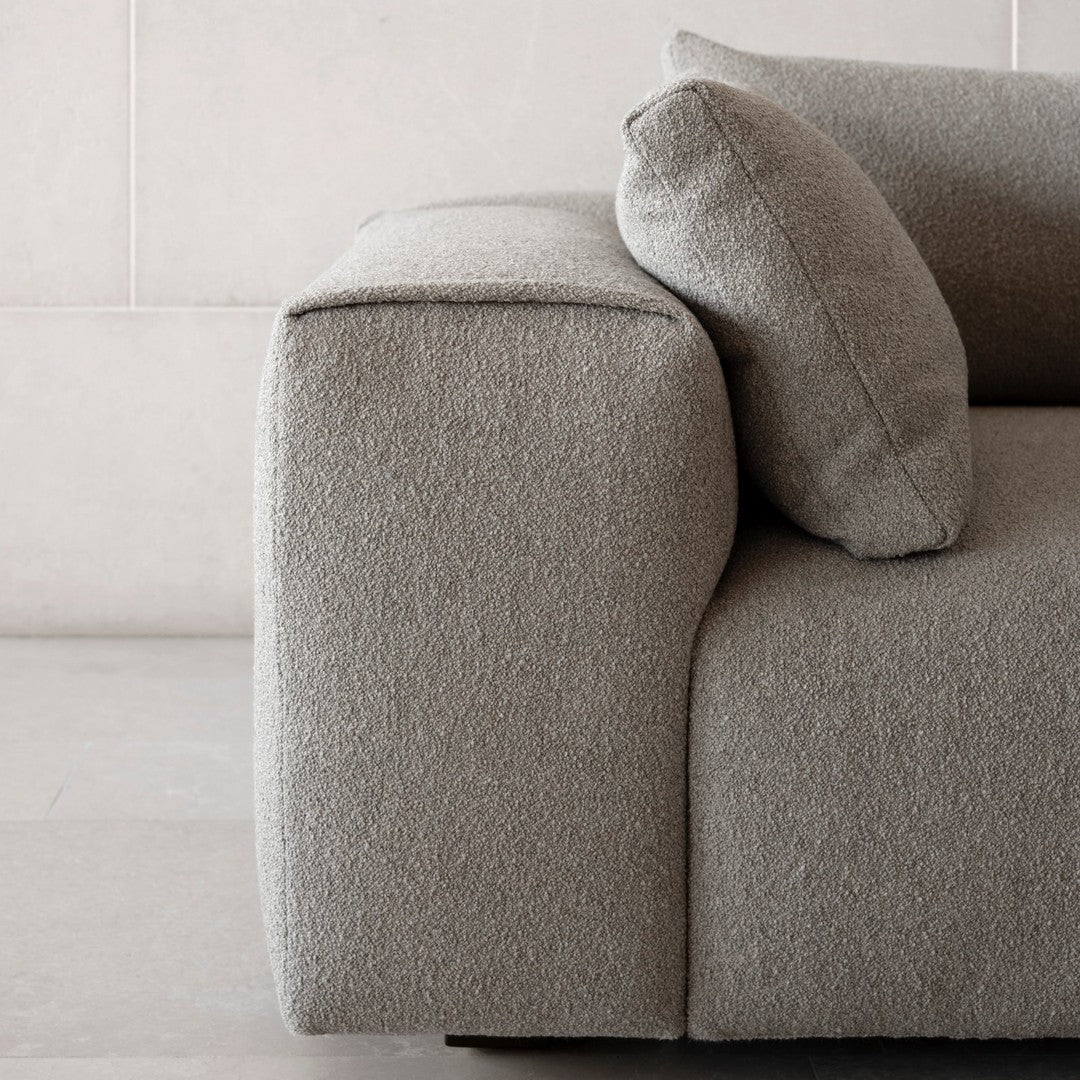Soft gray textured fabric sofa with a minimalist design and plush pillows, ideal for modern interiors.