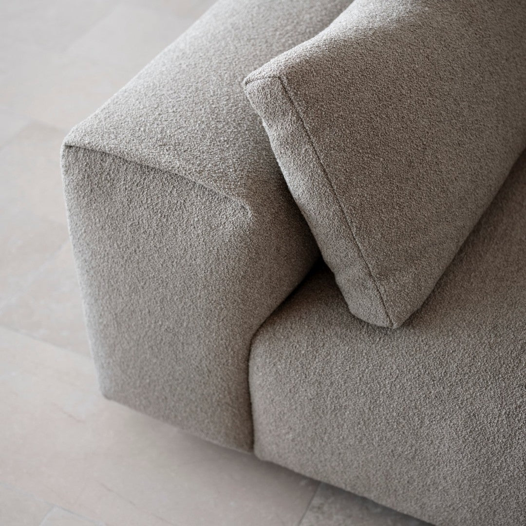 Textured light beige fabric on a modern sofa, featuring soft contours and a minimalist design.