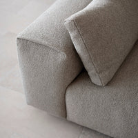 Textured light beige fabric on a modern sofa, featuring soft contours and a minimalist design.