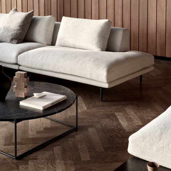 Light beige sectional sofa with textured fabric and sleek black metal legs, complemented by a dark marble coffee table.