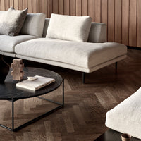 Cream-colored fabric sofa with clean lines, set against a dark wood floor and geometric black coffee table.