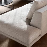 Light beige sofa with a textured fabric and minimalist design, featuring subtle patterns and soft shadows.